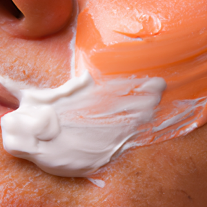 A close-up of a peach-colored cream being spread on a person's face.