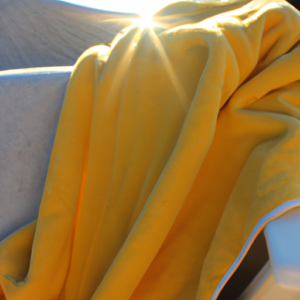A beach chair with a towel draped over it with a bright yellow sun shining down.